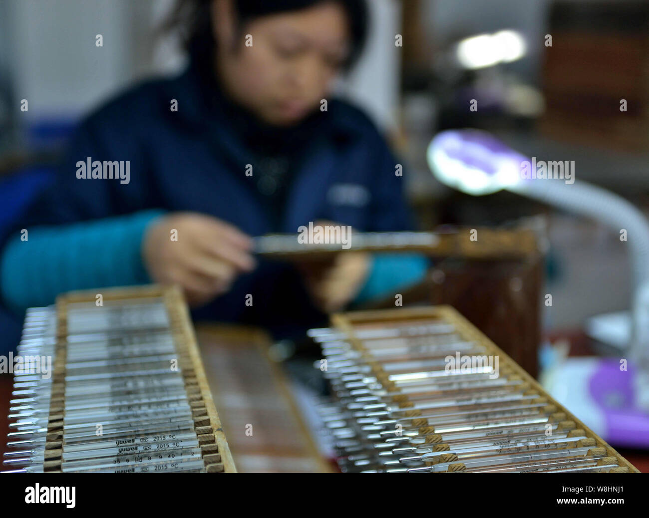 A Chinese worker has tubes of mercury-in-glass thermometers printed at the plant of Jiangsu Yuyue Medical Equipment & Supply Co., Ltd. in Yancheng cit Stock Photo