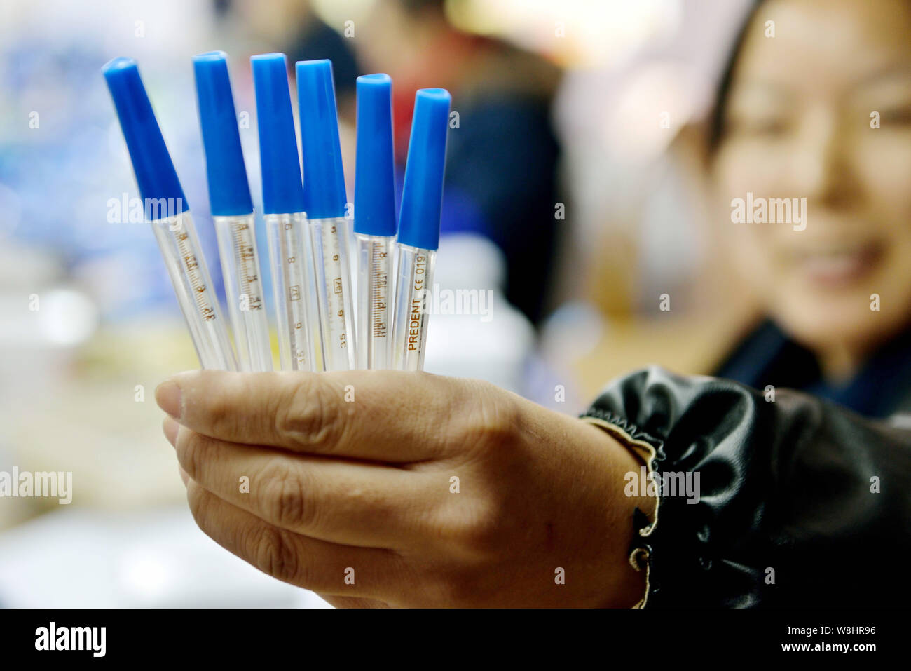 A Chinese worker shows finished mercury-in-glass thermometers at the plant of Jiangsu Yuyue Medical Equipment & Supply Co., Ltd. in Yancheng city, eas Stock Photo