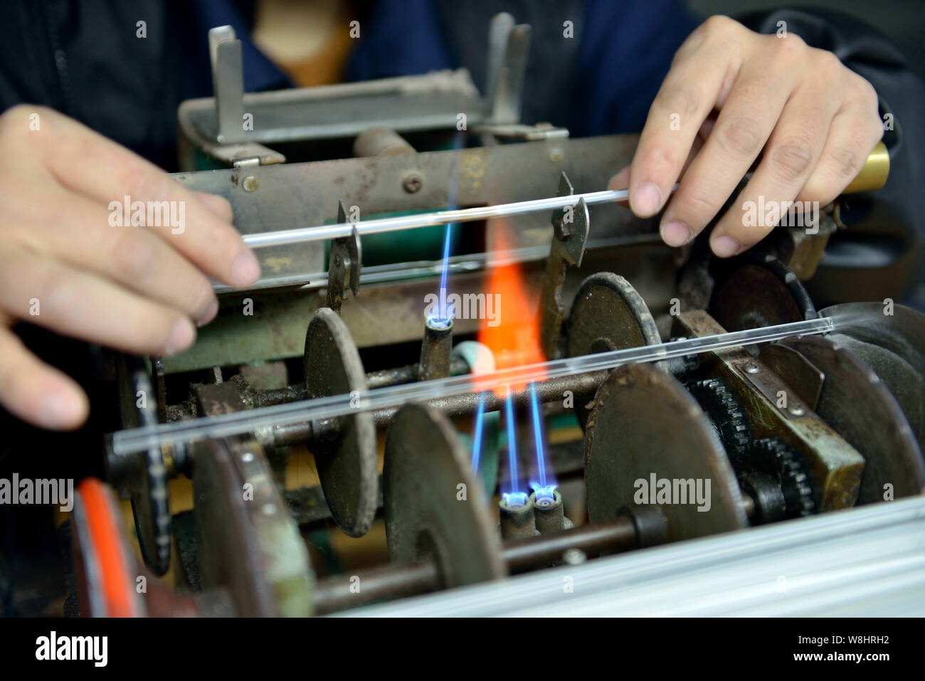 A Chinese worker heats up a mercury-in-glass thermometer in flame to prolong the neck of the tube at the plant of Jiangsu Yuyue Medical Equipment & Su Stock Photo