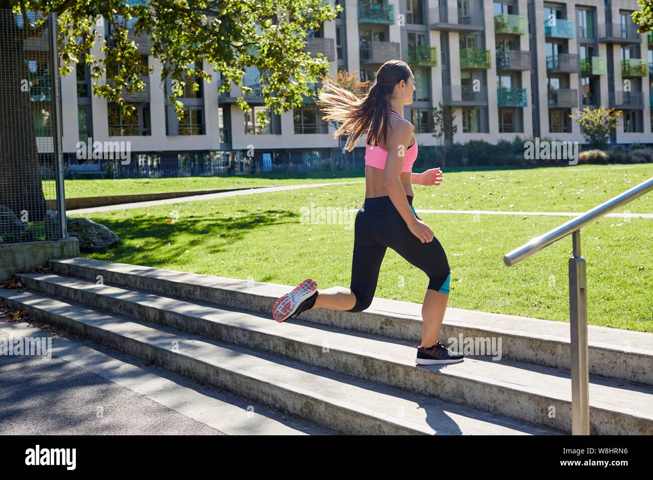 Young woman jogging up steps. Stock Photo