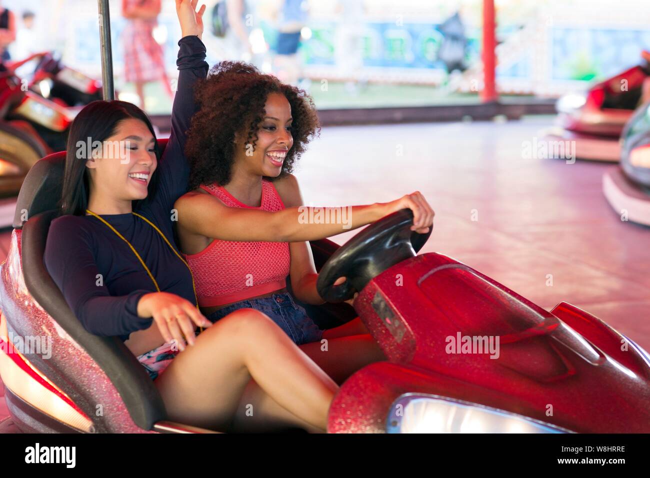 Two young women on bumper car at fun fair. Stock Photo