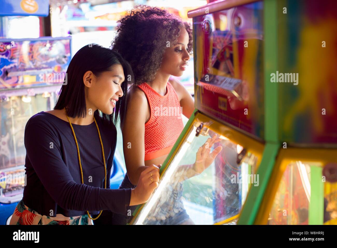 Two young women playing arcade game at fun fair. Stock Photo
