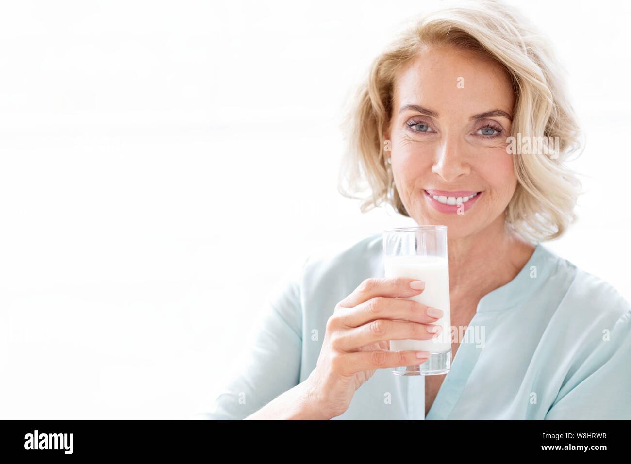 Mature woman smiling with glass of milk. Stock Photo