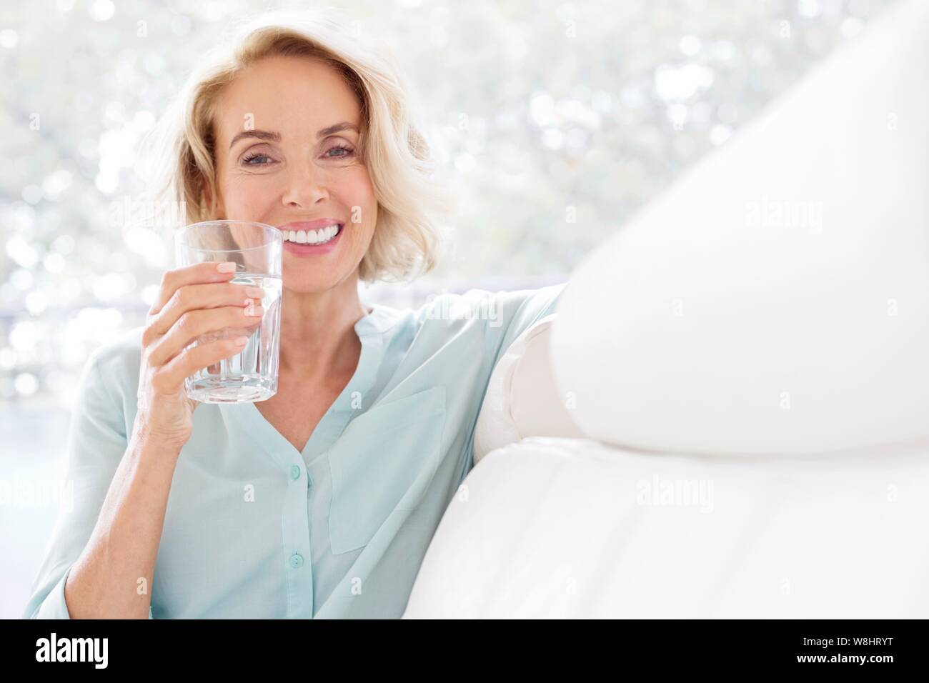 Mature woman smiling with glass of water. Stock Photo
