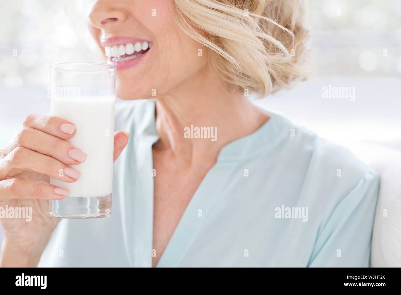 Mature woman smiling with glass of milk. Stock Photo