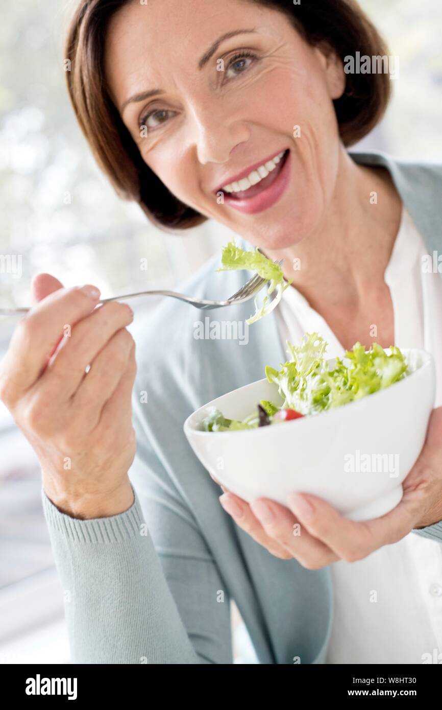 Mature woman eating salad. Stock Photo