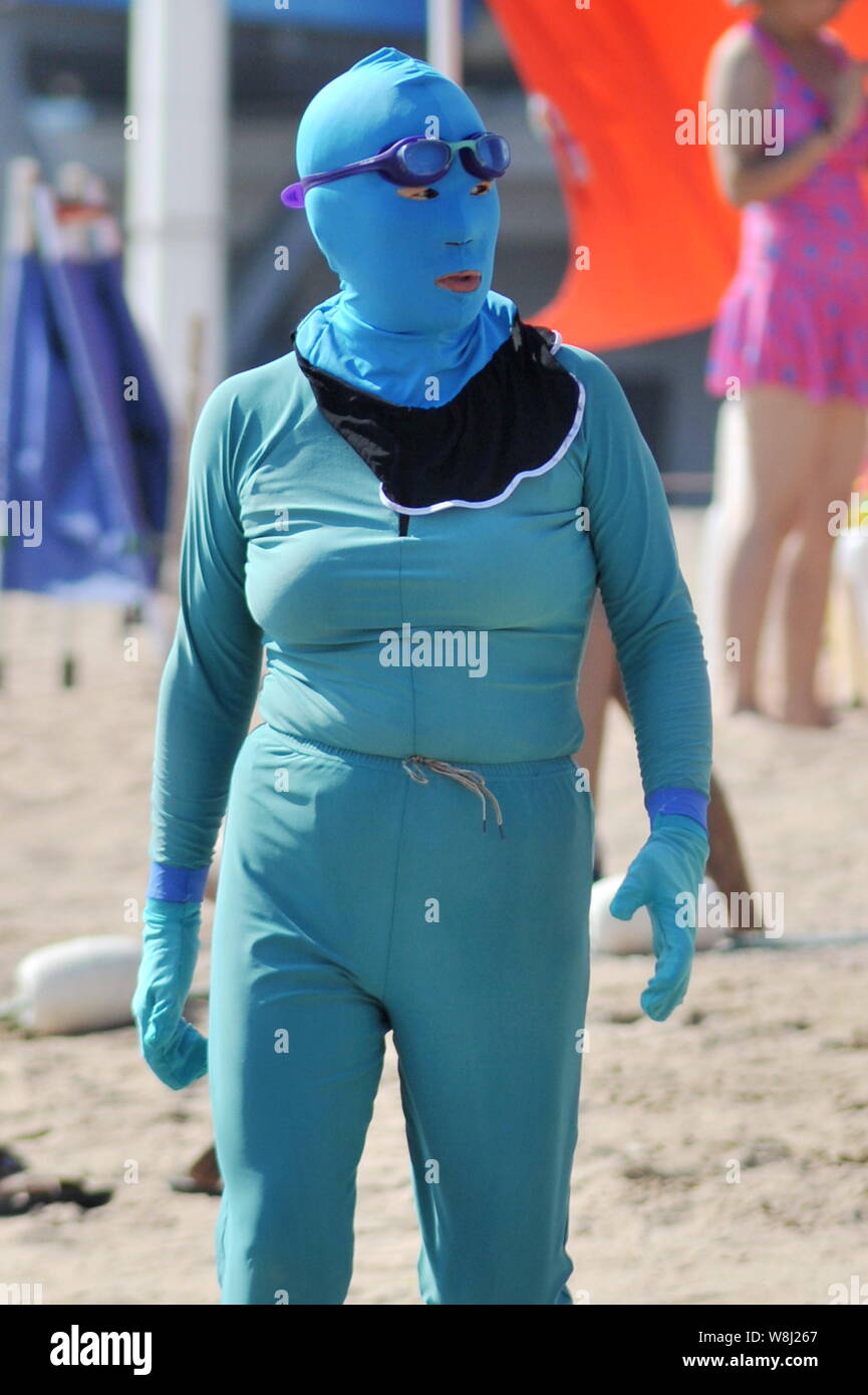 A female Chinese swimmer wearing a facekini walks at a beach resort in