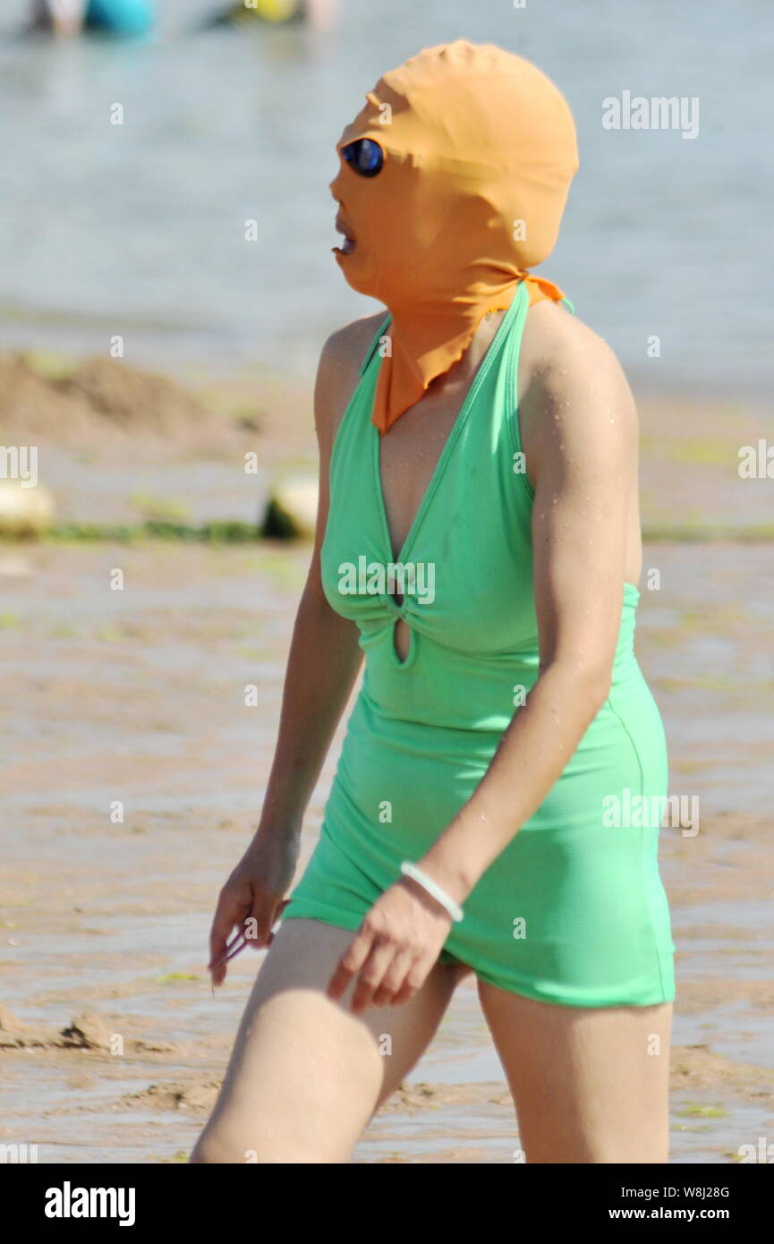 A female Chinese swimmer wearing a facekini walks at a beach resort in Qingdao city, east China's Shandong province, 8 July 2015.   The National Meteo Stock Photo