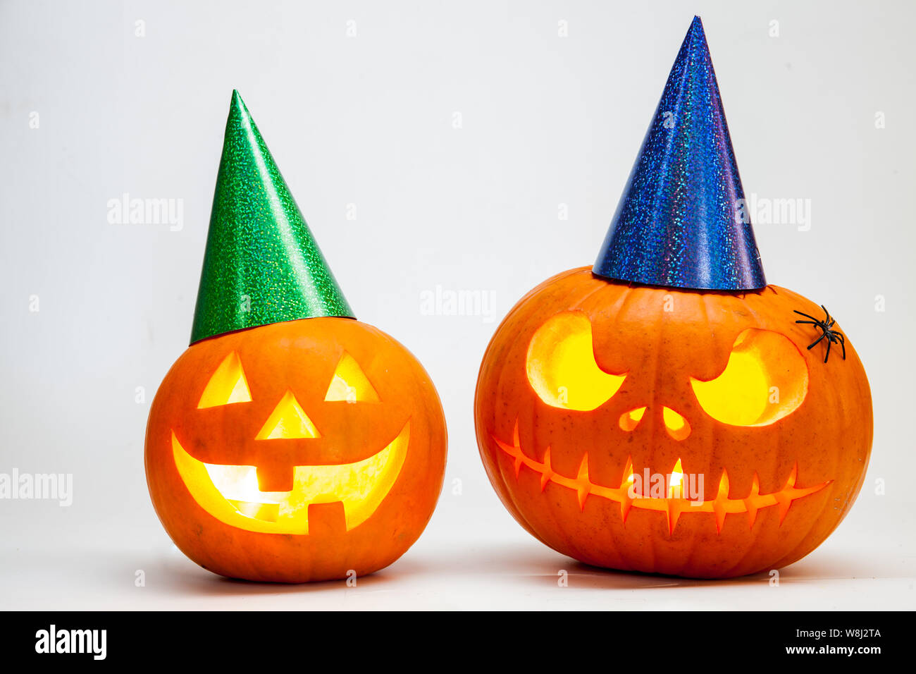 Two Halloween pumpkin head jack lantern with burning candles with festive hubcap isolated on white background Stock Photo