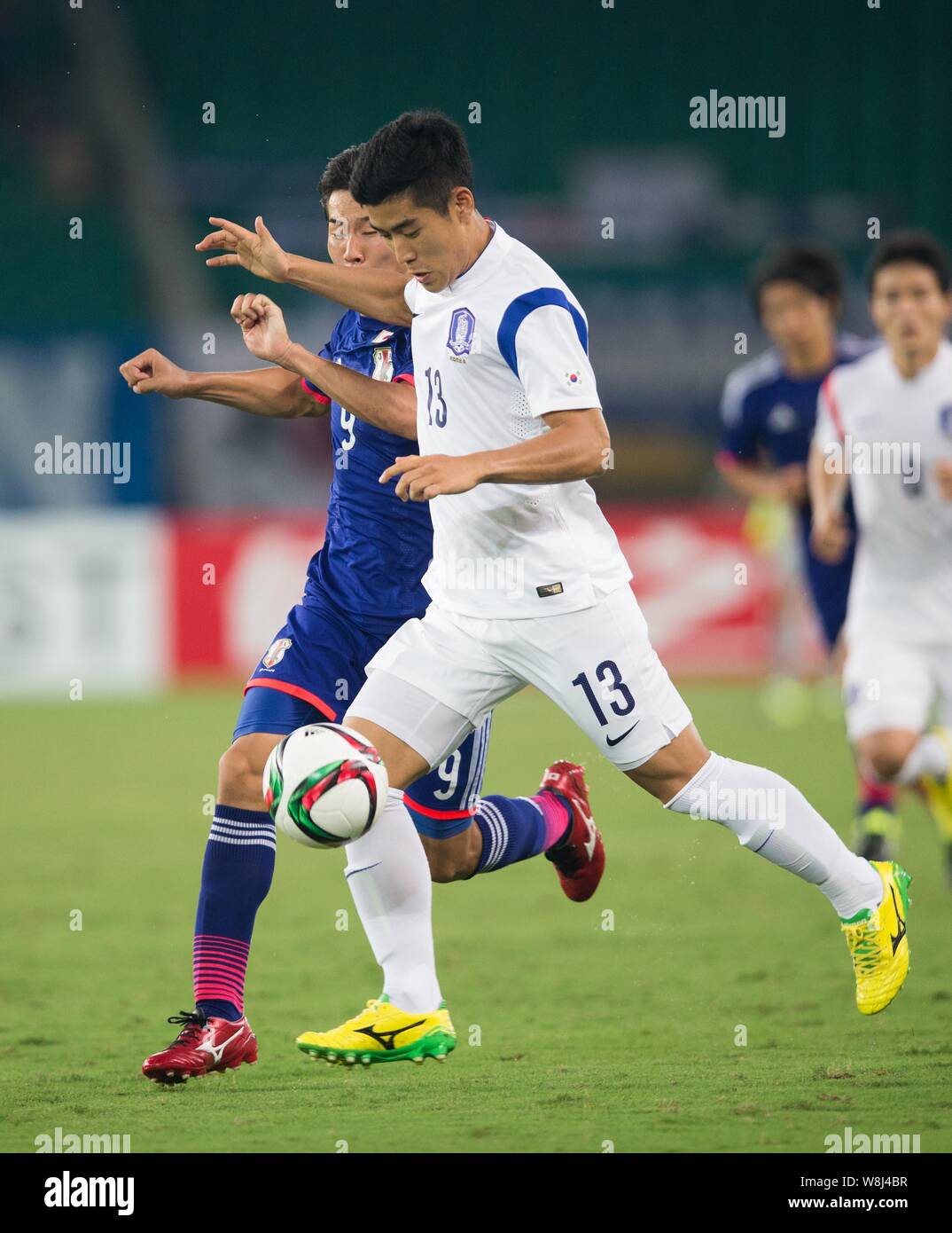 Kensuke Nagai of Japan, left, challenges Lee Yong-joo of South Korea during their soccer match of the Men's East Asian Cup 2015 in Wuhan city, central Stock Photo