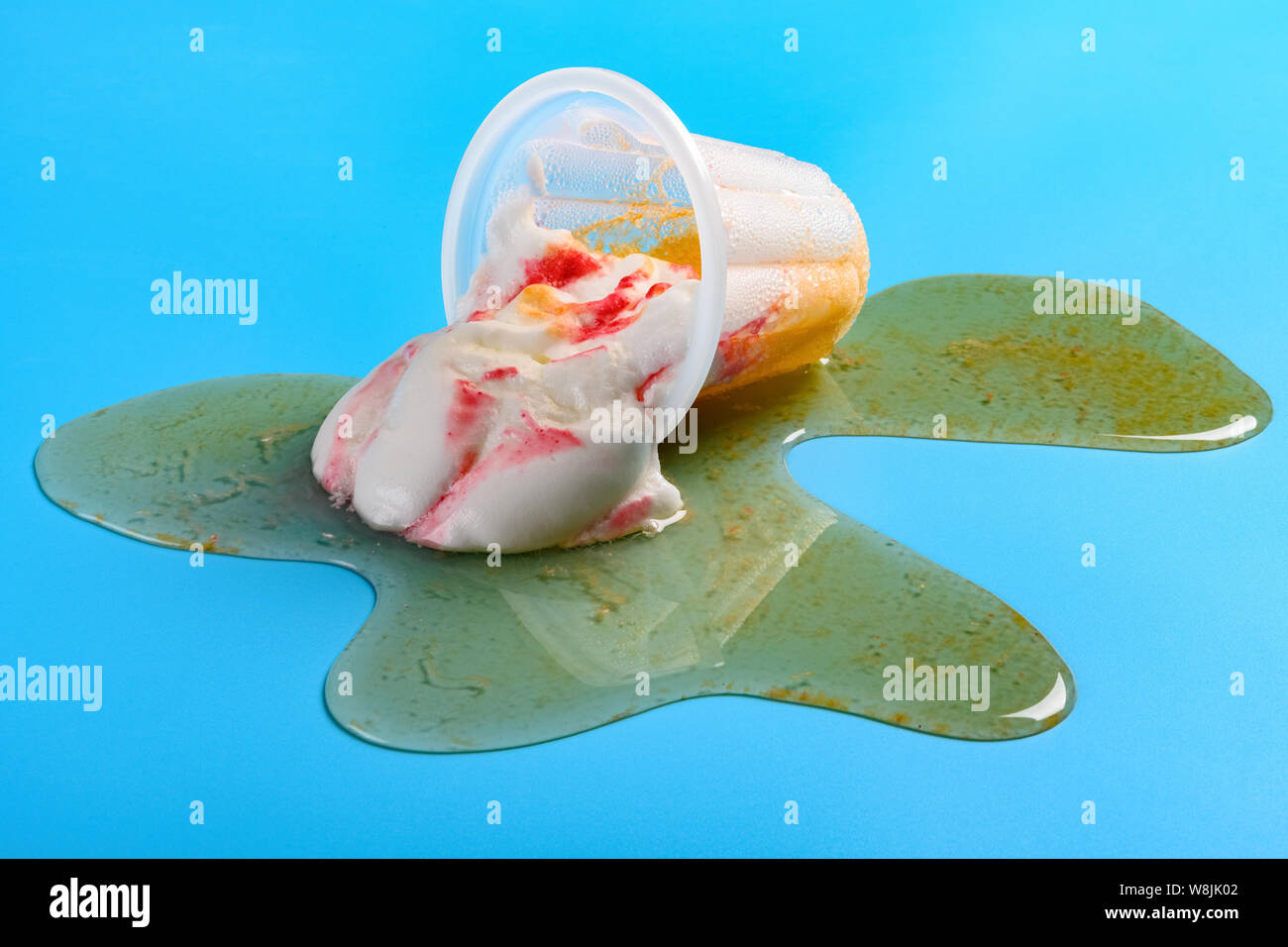 side view cup of strawberry flavor ice cream with smoothie melted on blue background Stock Photo