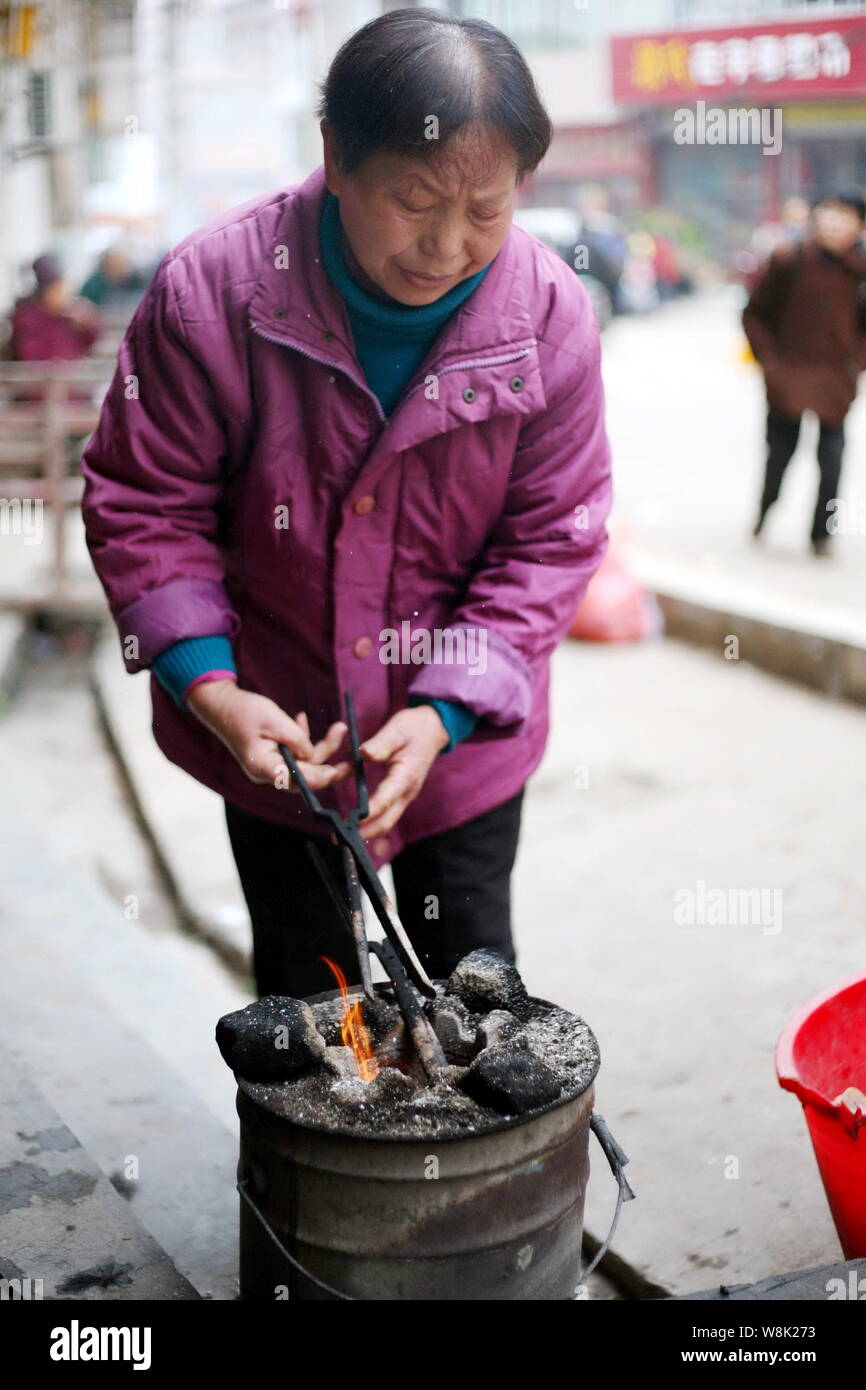 The Wife Of Chinese Barber Wang Weimei Heats Up Fire Tongs In A Stove Before They