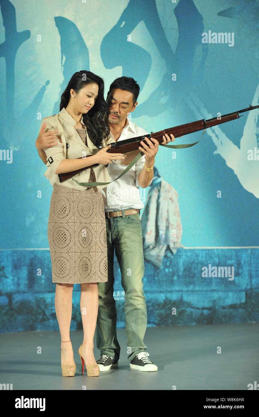 Hong Kong actor Sean Lau, right, instructs Chinese actress Tang Wei to hold a gun during a press conference for their movie 'Tale of Three Cities' in Stock Photo