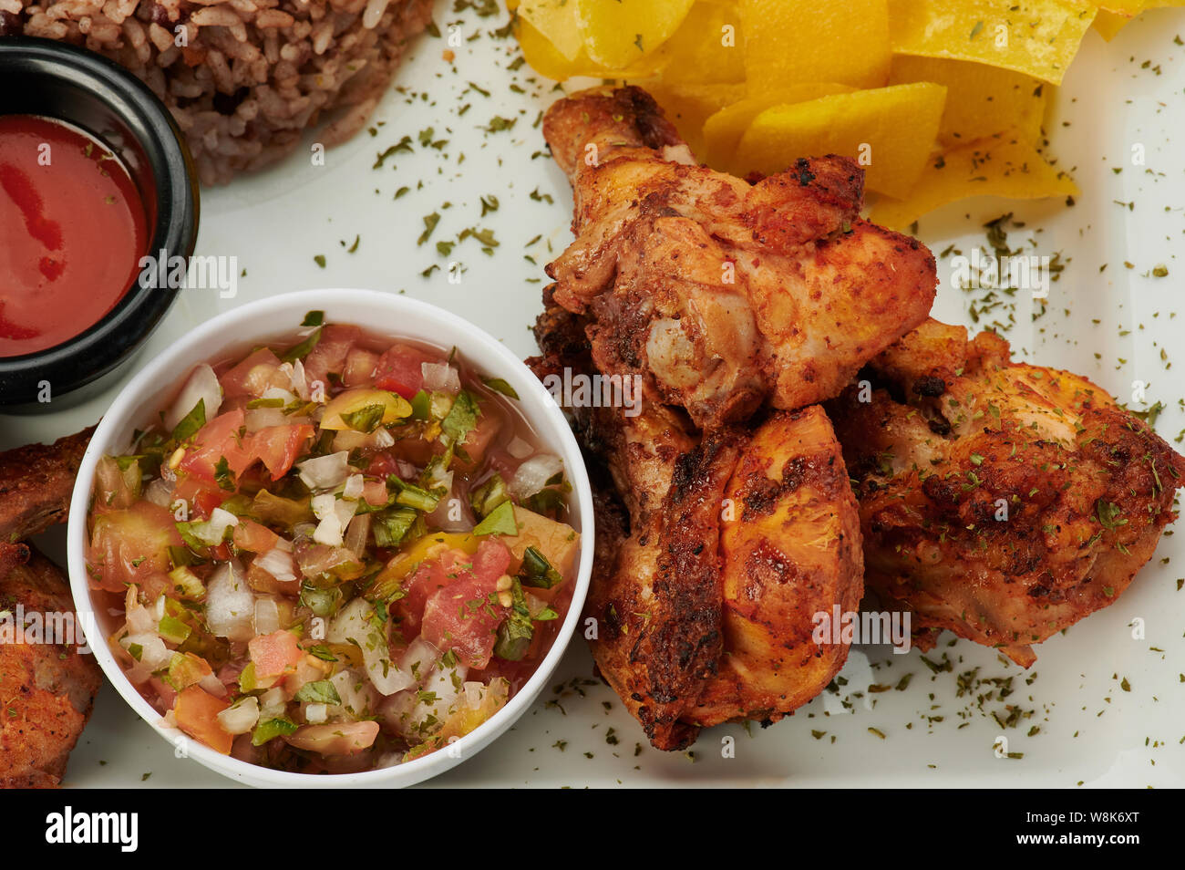 Fried chicken legs with salsa on plate close up view Stock Photo