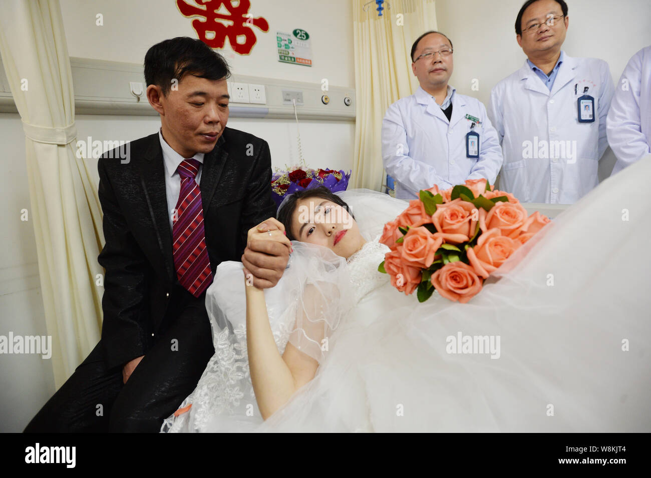 Terminally ill Chinese woman Yang Liu dressed in a wedding gown, right, holds her husband Peng Xin during their wedding ceremony in a ward at a hospit Stock Photo