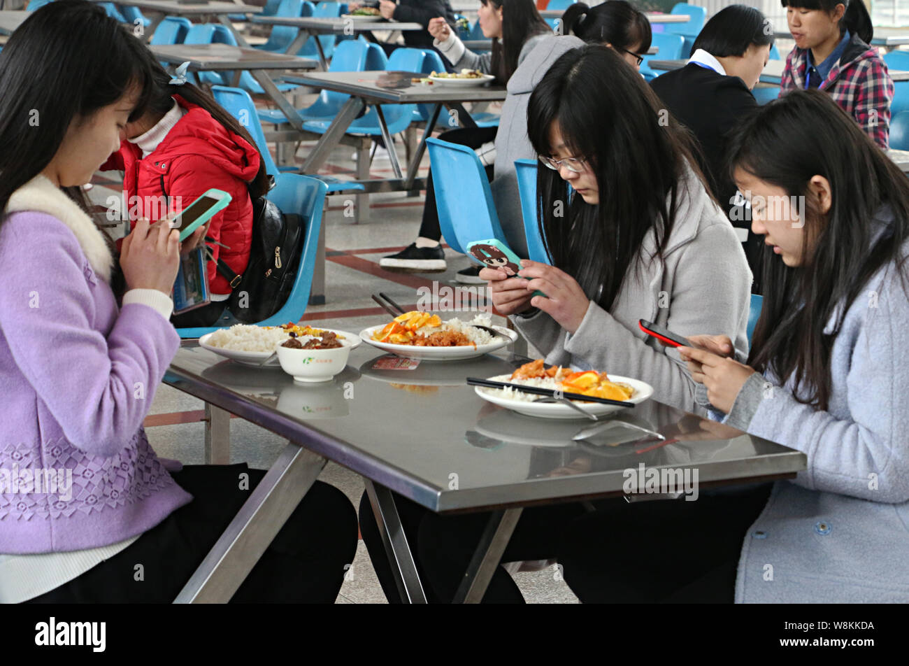 Students take photos of new dishes before eating at a canteen in Anqing Normal University in Anqing City, east China's Anhui province, 7 March 2016. Stock Photo