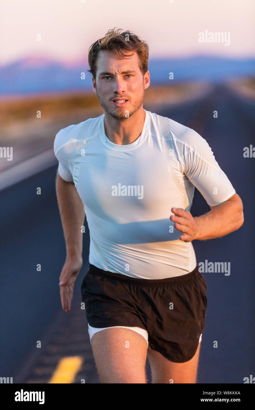 Athlete endurance runner man long distance running with focus and  determination on desert road at sunset. Sportsman training in compression  sports t-shirt and shorts activewear in summer landscape Stock Photo - Alamy