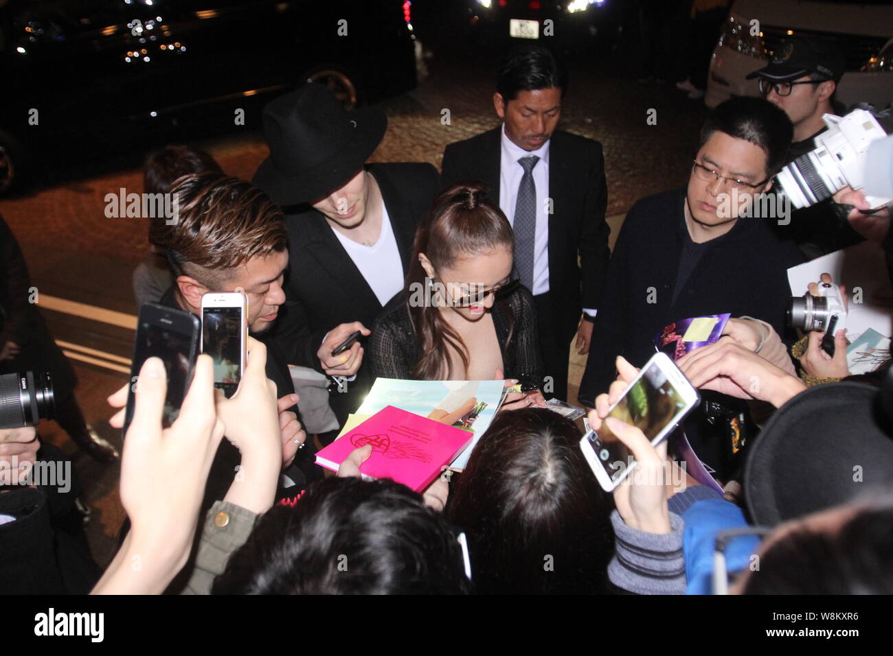 Japanese singer Ayumi Hamasaki, center, signs autographs for fans on a street after midnight in Hong Kong, China, 24 February 2016. Stock Photo