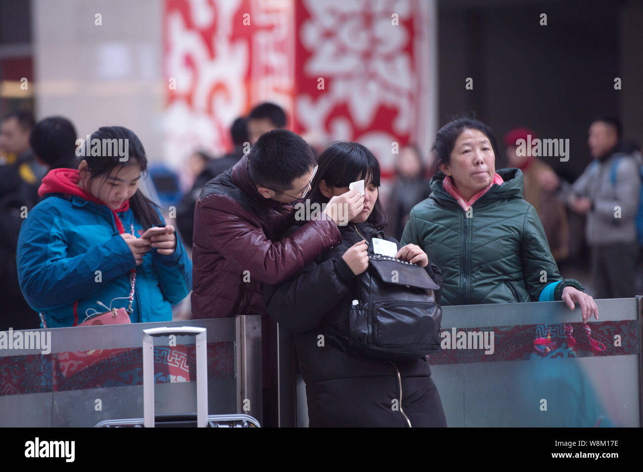 A young Chinese man helps his girlfriend wipe off tears as they bid farewell to each other at the Changchun Railway Station as they are going to part Stock Photo