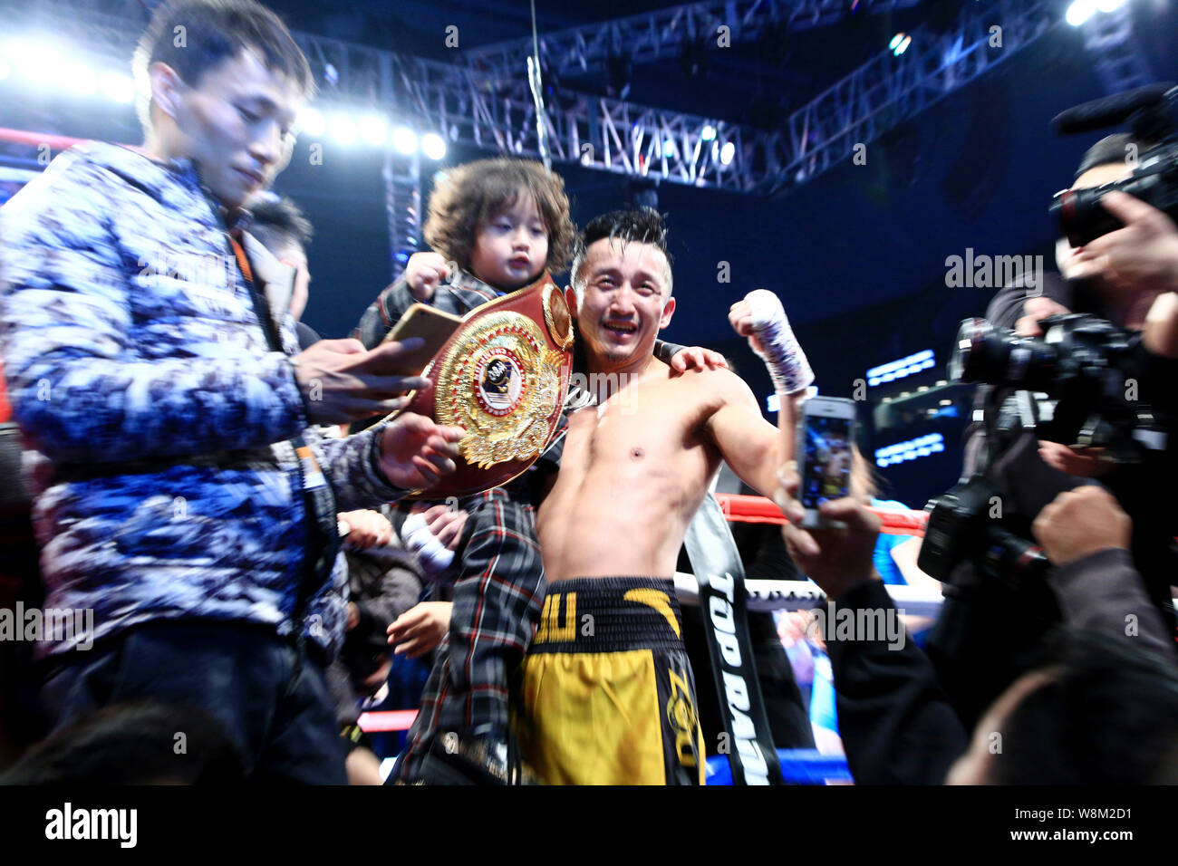 China's Zou Shiming, center, poses with his son to celebrate after defeating Brizil's Natan Santana Coutinho during their bout in Shanghai, China, 30 Stock Photo