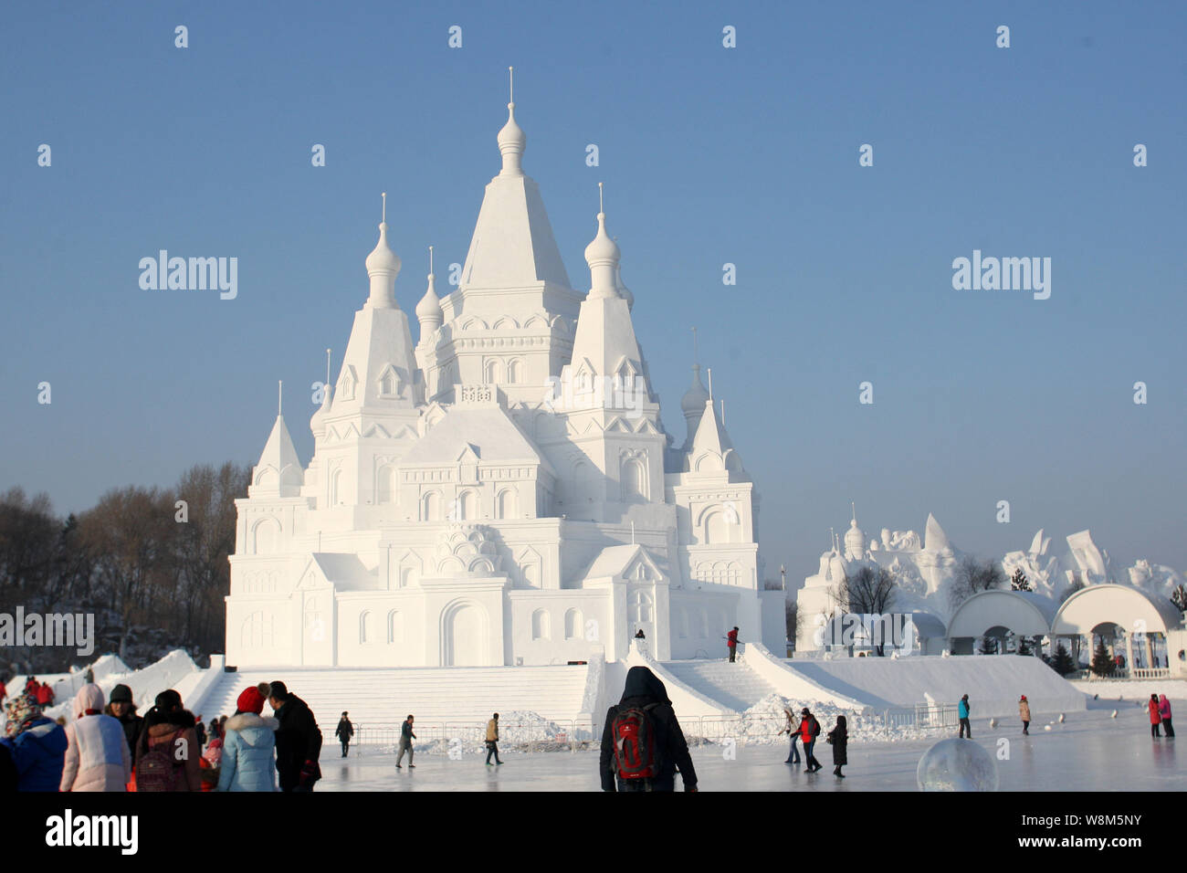 Tourists walk past the 51-meter-tall ice building, dubbed as 'Crown of Ice-snow' castle, at the Sun Island scenic spot in Harbin city, northeast China Stock Photo