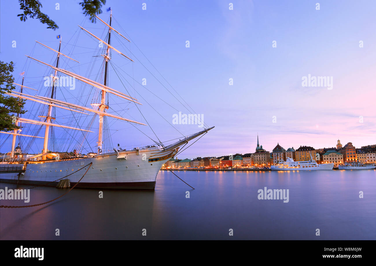 Scenic view of Stockholm's Old Town (Gamla Stan) at dusk with illuminated old ship on the foreground, Sweden Stock Photo