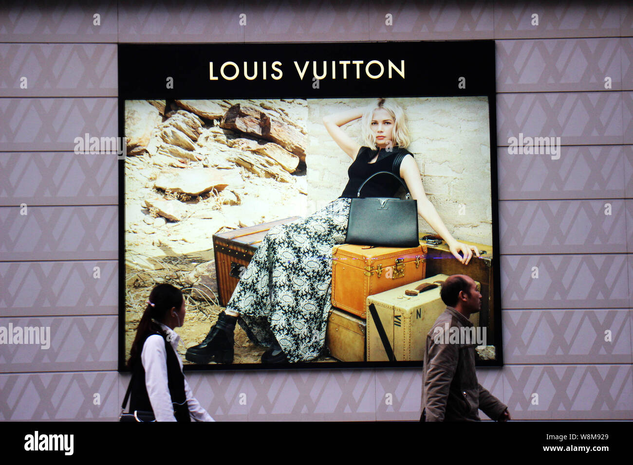 --FILE--Pedestrians walk past a Louis Vuitton (LV) store in Chongqing, China, 23 November 2015.    Foreign investment into China accelerated in 2015 a Stock Photo