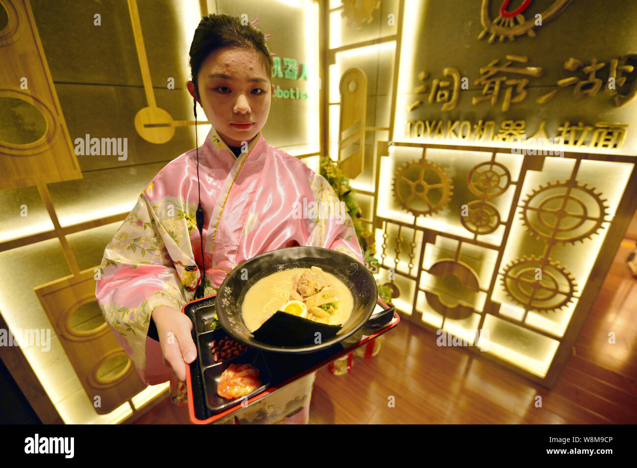 A waitress serves a bowl of noodles cooked by robots Koya and Kona at a