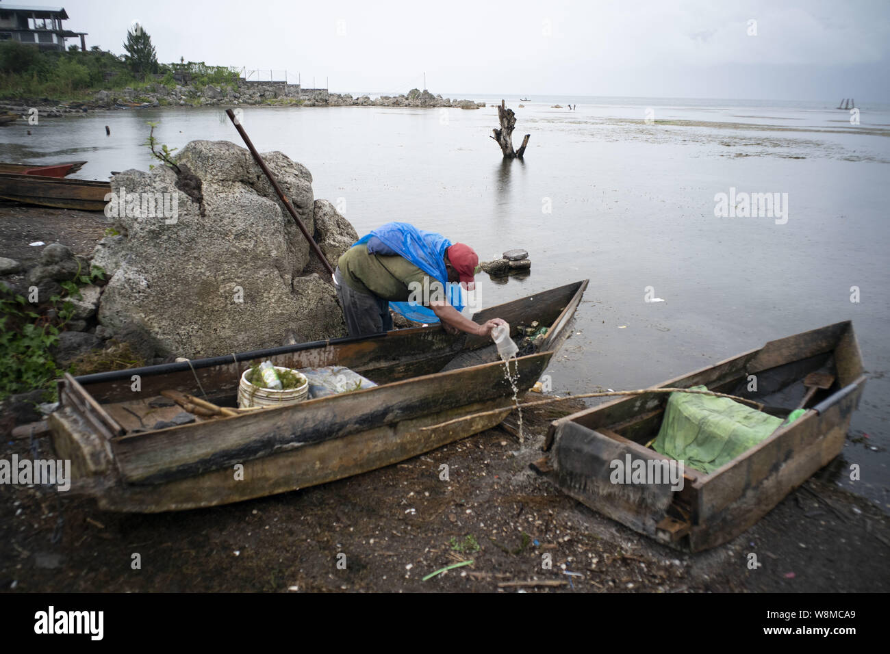 Cerro De Oro, Solola, Guatemala. 8th Aug, 2019. A fisherman bails water from a cayuco, an old Mayan boat at Cerro de Oro on the shores of Lake Atitlan, Solola Guatemala. The lake, surrounded by volcanoes, is highly polluted due to the lack of sanitation in almost all villages surrounding the lake. Credit: Bob Daemmrich/ZUMA Wire/Alamy Live News Stock Photo