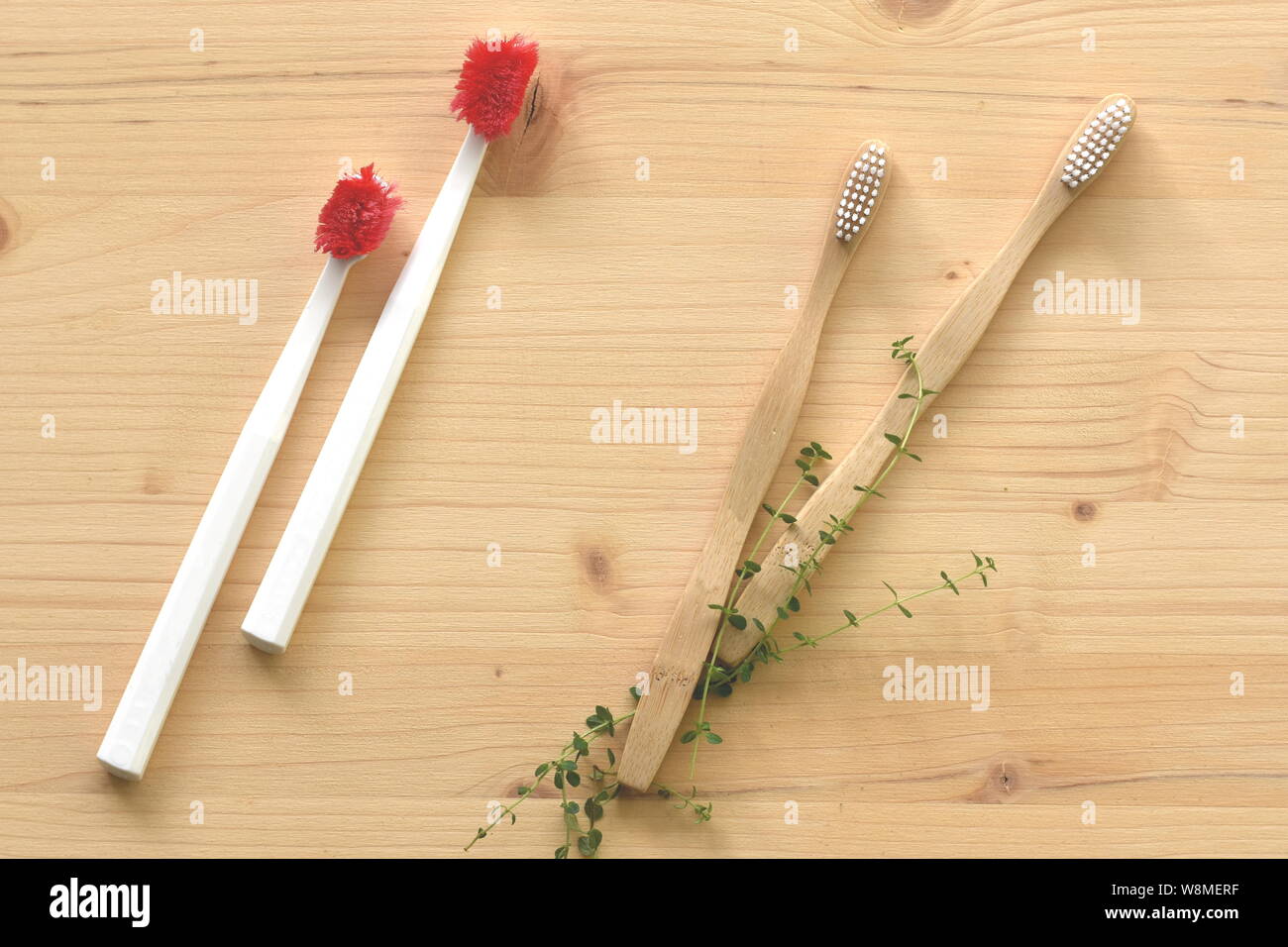 Two heavy used wasted disposable plastic toothbrushes vs two new wooden