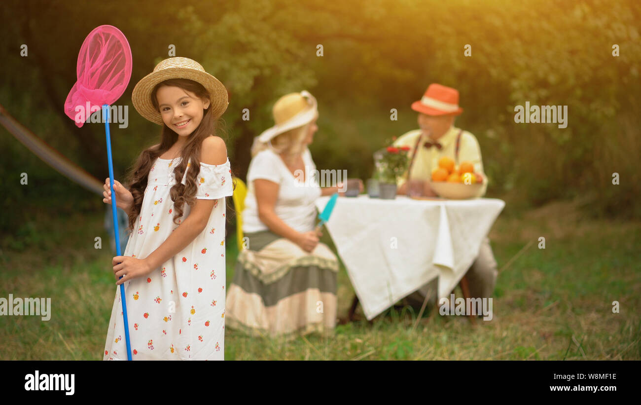 A Cute Dark-haired Girl In A Sundress With A Pink Butterfly Net. Stock Photo