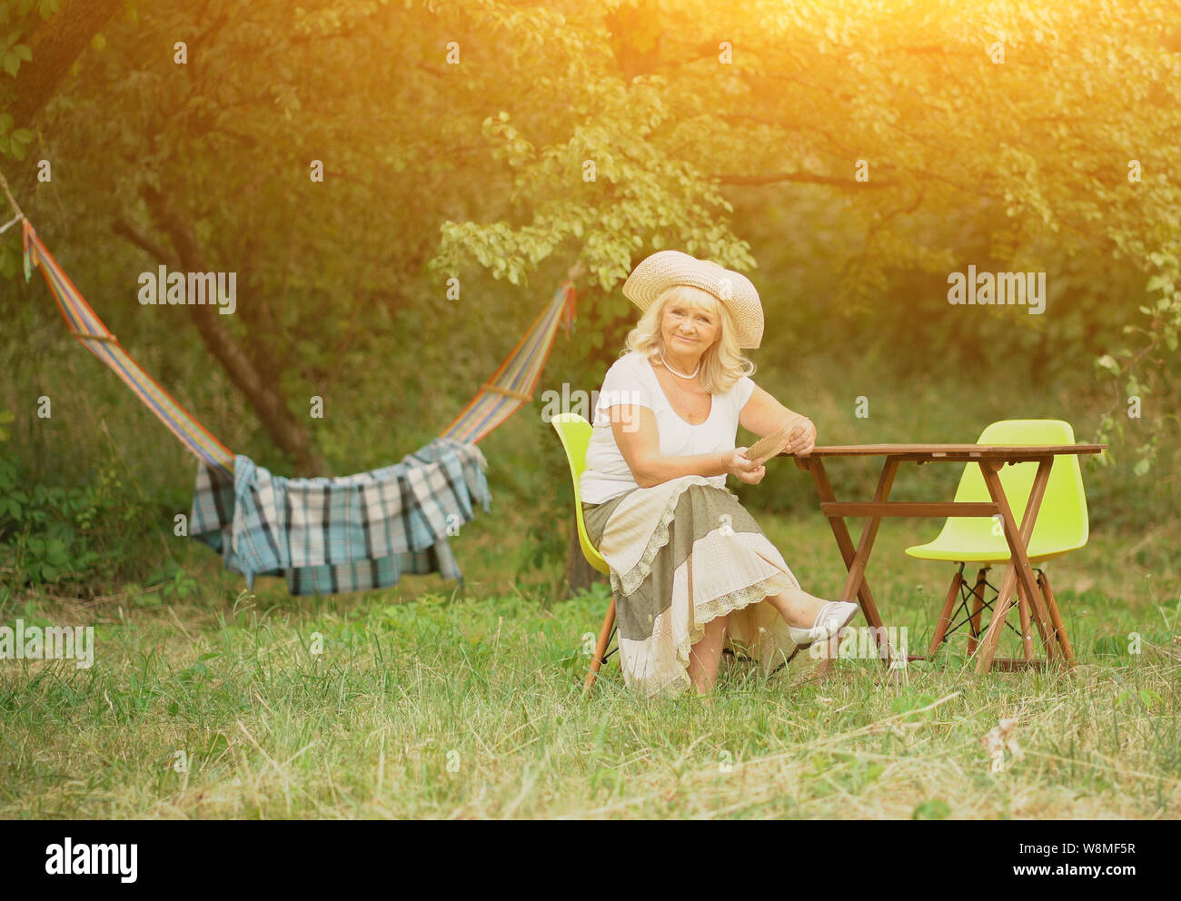 The old lady is sitting in the garden near the hammock Stock Photo - Alamy