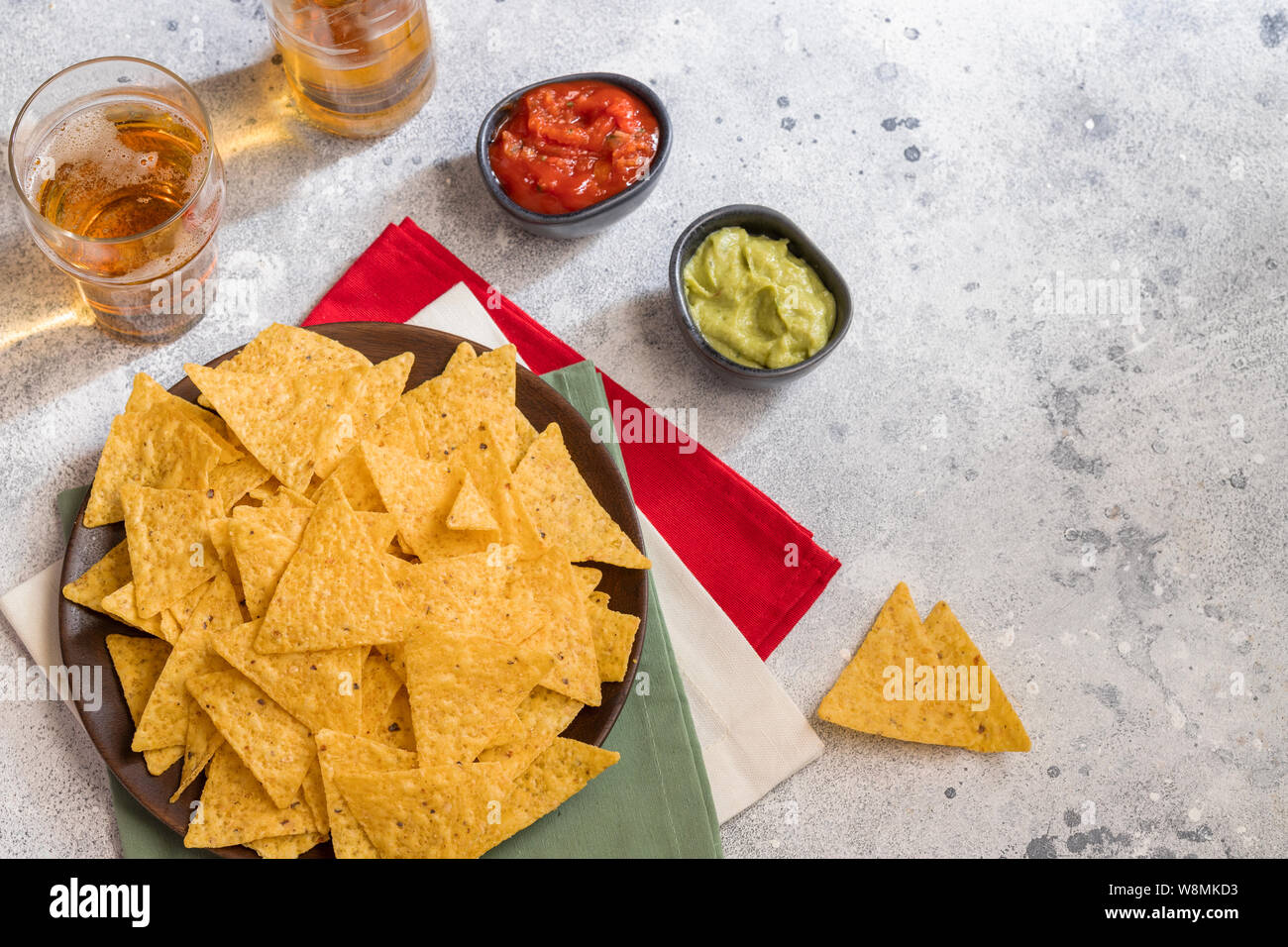 Famous Mexican snack, nachos with guacamole, red chilli sauce and beer