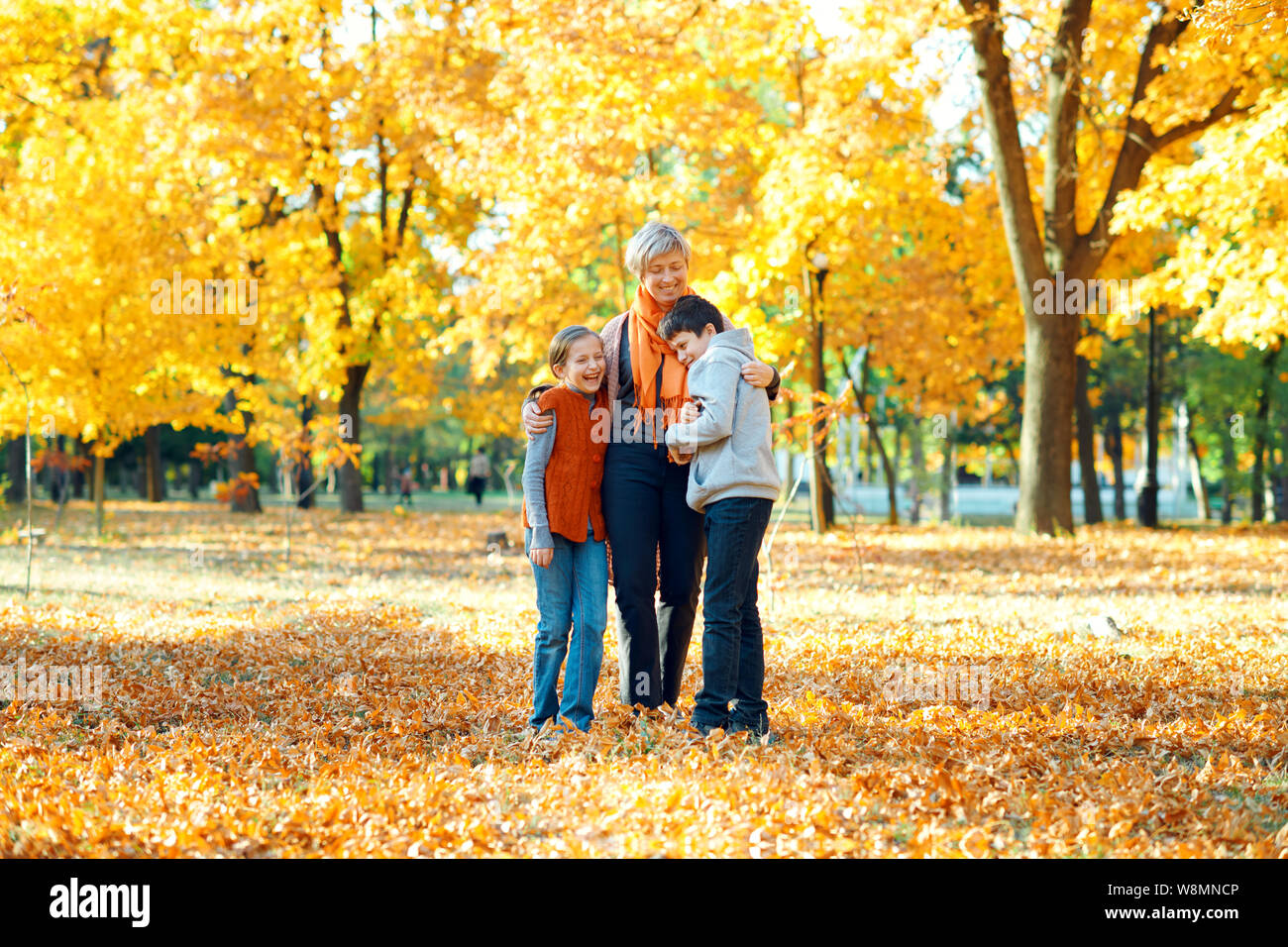 Happy family posing, playing and having fun in autumn city park ...