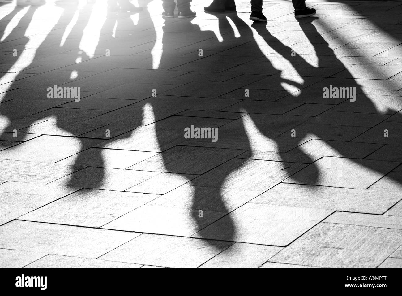 Shadows and silhouettes of people at a city during sunset Stock Photo