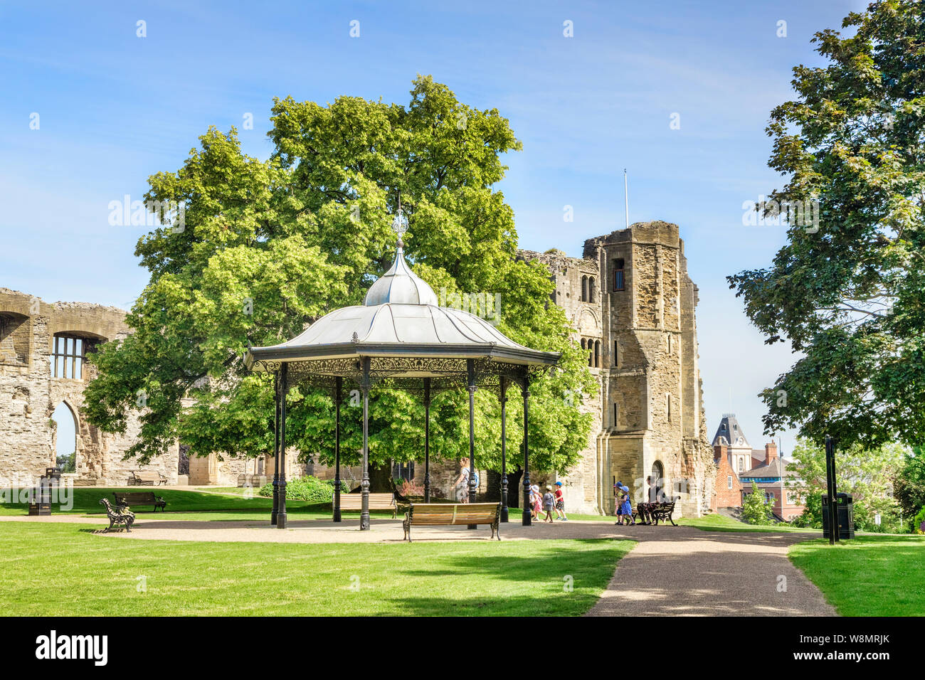 4 July 2019: Newark on Trent, Nottinghamshire, UK - The 12th century castle and gardens, and the bandstand, with a distant party of children on a visi Stock Photo