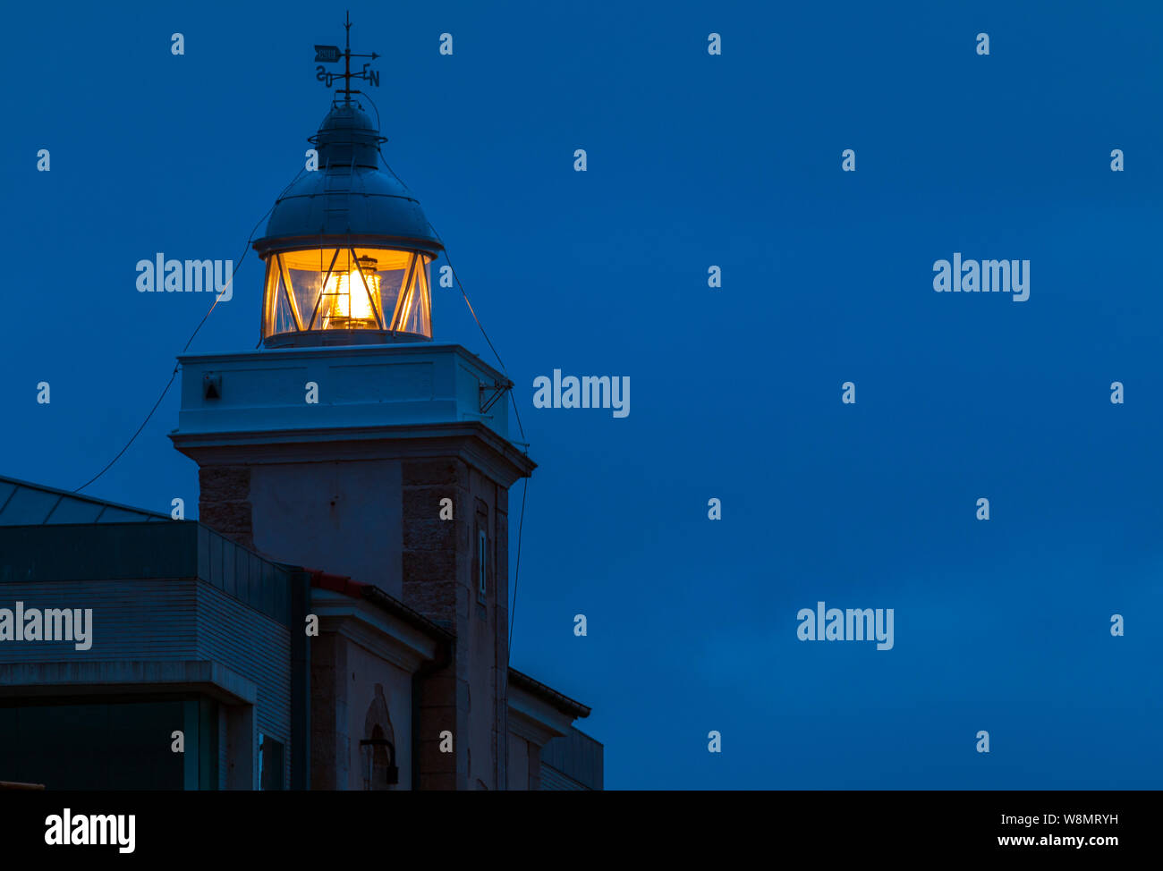 Lantern of the San Vicente de la Barquera lighthouse shinning in the dark. Cantabria, Spain Stock Photo