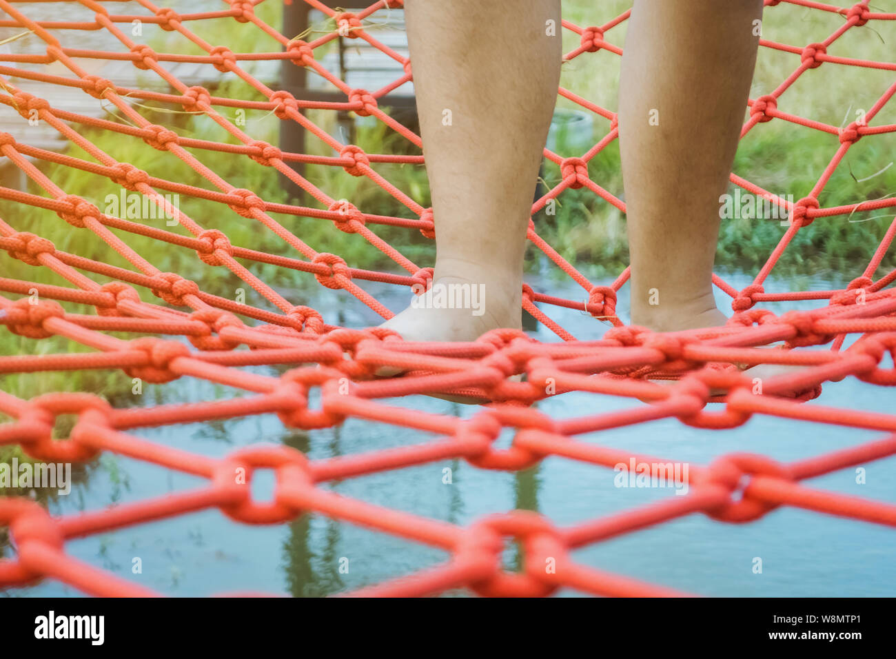 Swampy Rope Young woman tried to walk on the bridge floor tied with a red rope to ...