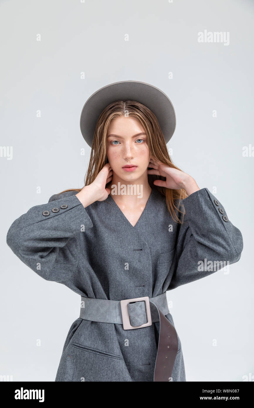 Portrait of young lady in grey autumn outfit posing hands on neck isolated on white background Stock Photo