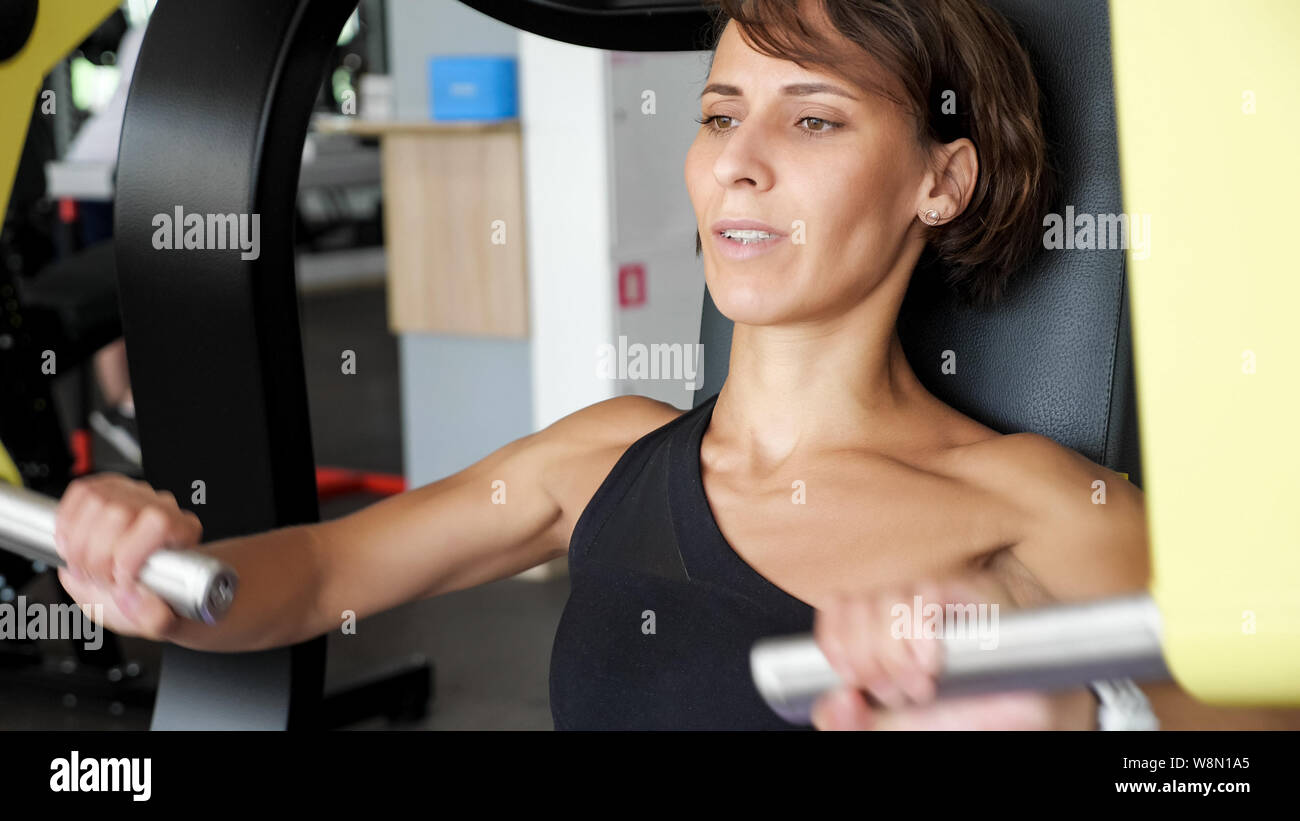 Woman Doing Training On Machine For Her Triceps Muscle At The Gym