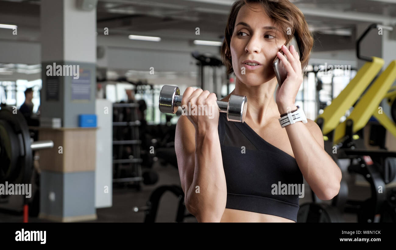 Mature Woman Exercising Biceps With Dumbbells In The Gym And
