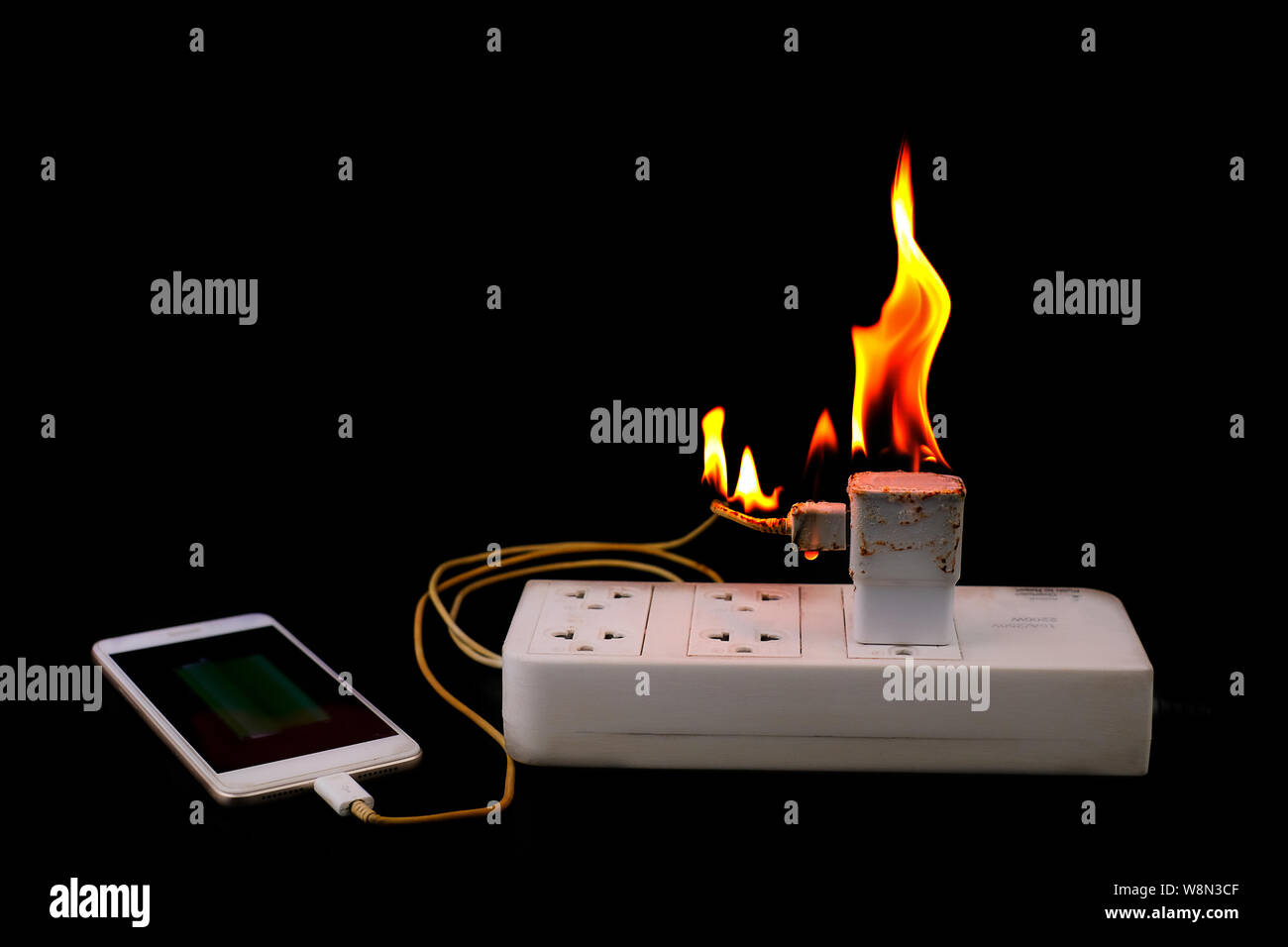 On fire Adapter smart phone charger at plug in power outlet at black