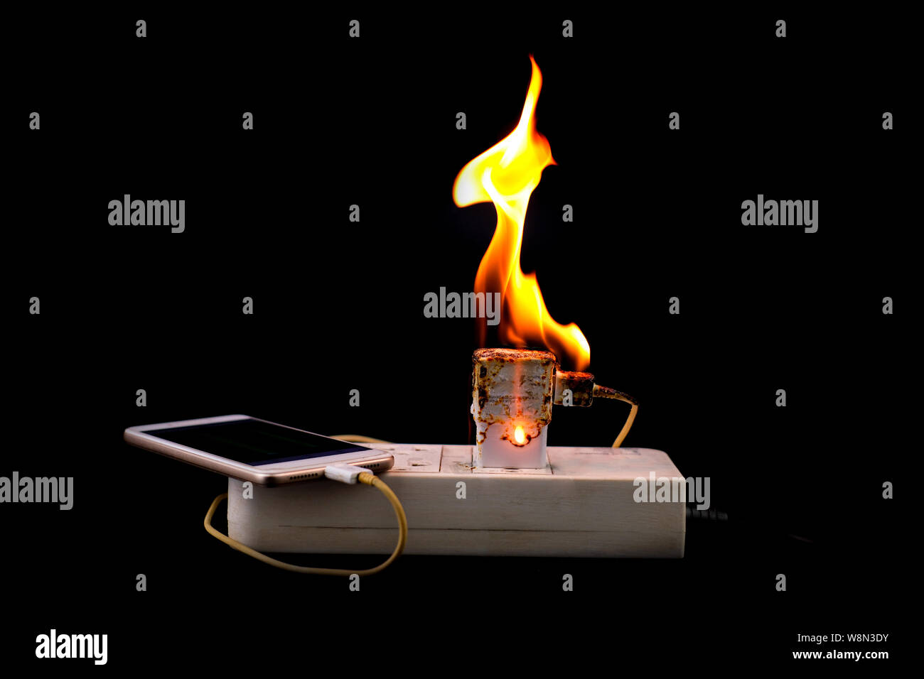 On fire Adapter smart phone charger at plug in power outlet at black