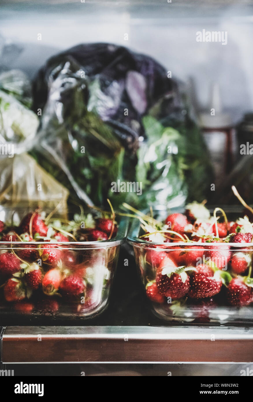 Fridge shelves loaded with fresh summer strawberries in glass