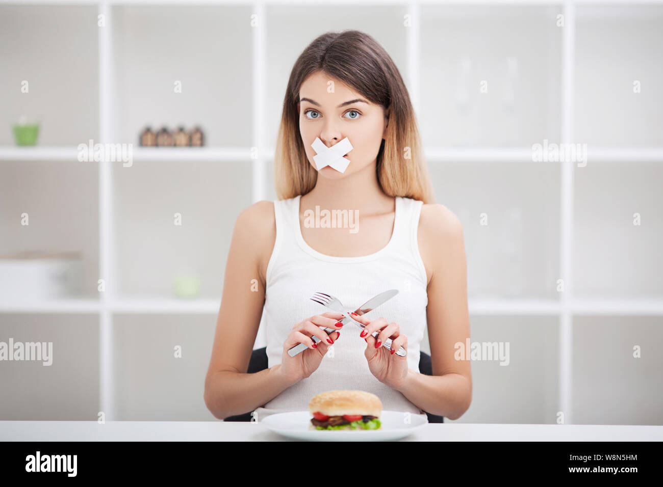 Diet. Young woman with duct tape over her mouth, preventing her to eat