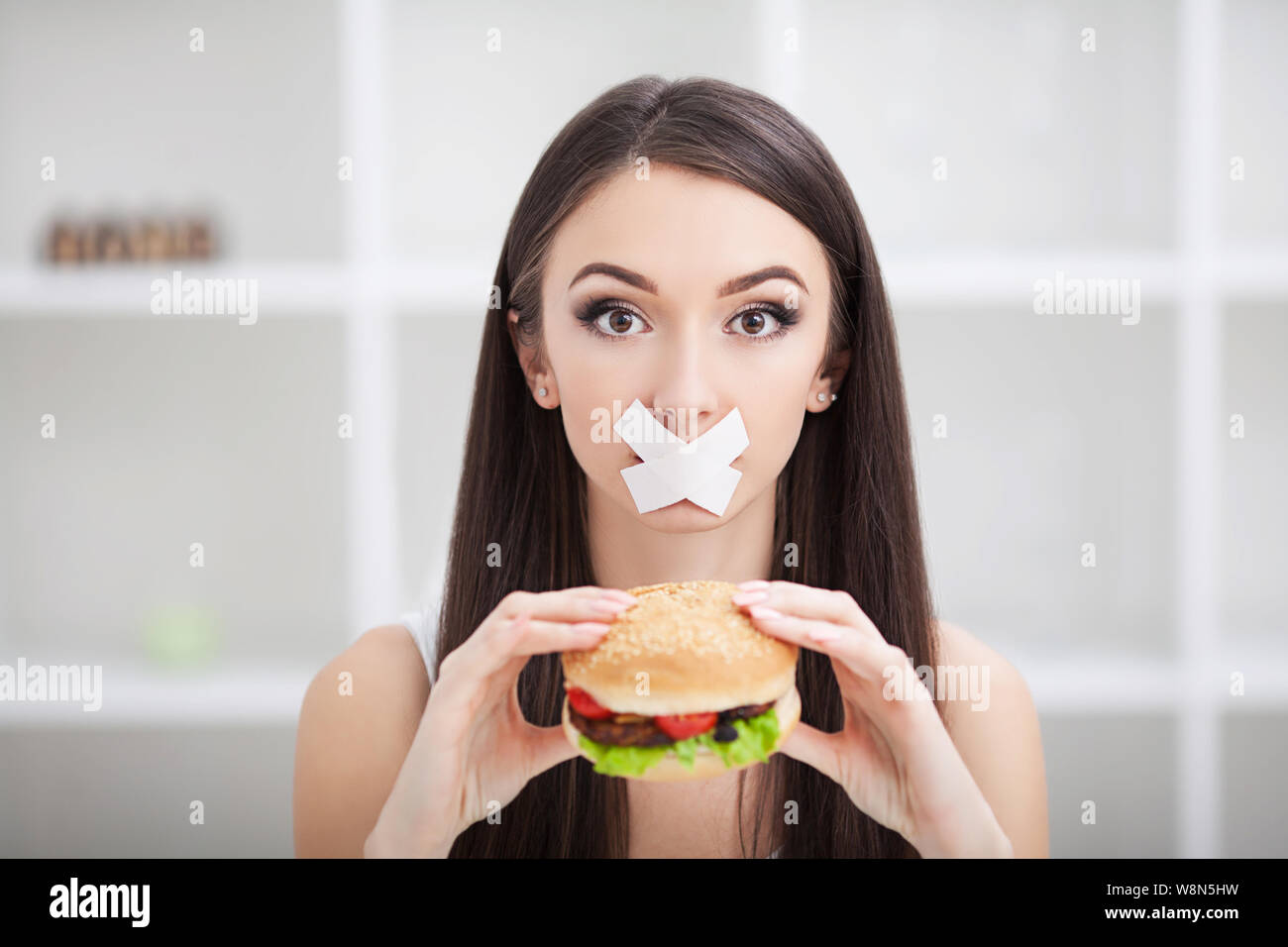 Diet. Young woman with duct tape over her mouth, preventing her to eat