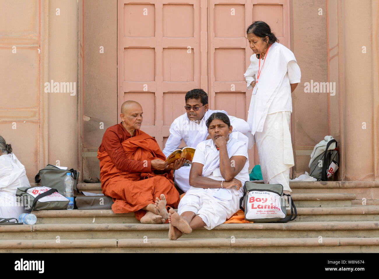 A Buddhist monk and pilgrims read scriptures at the Mulagandha Kuti Vihara Buddhist temple in Sarnath, Uttar Pradesh, India, Asia, South Asia Stock Photo