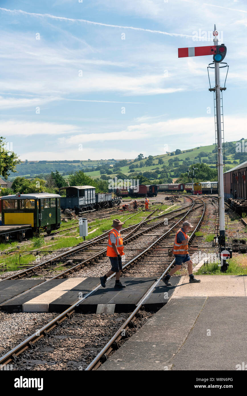 Winchcombe, Gloucestershire, England, UK. August 2019. Volunteers crossing the railway track of the Gloucestershire Warwickshire Steam Railway. Stock Photo