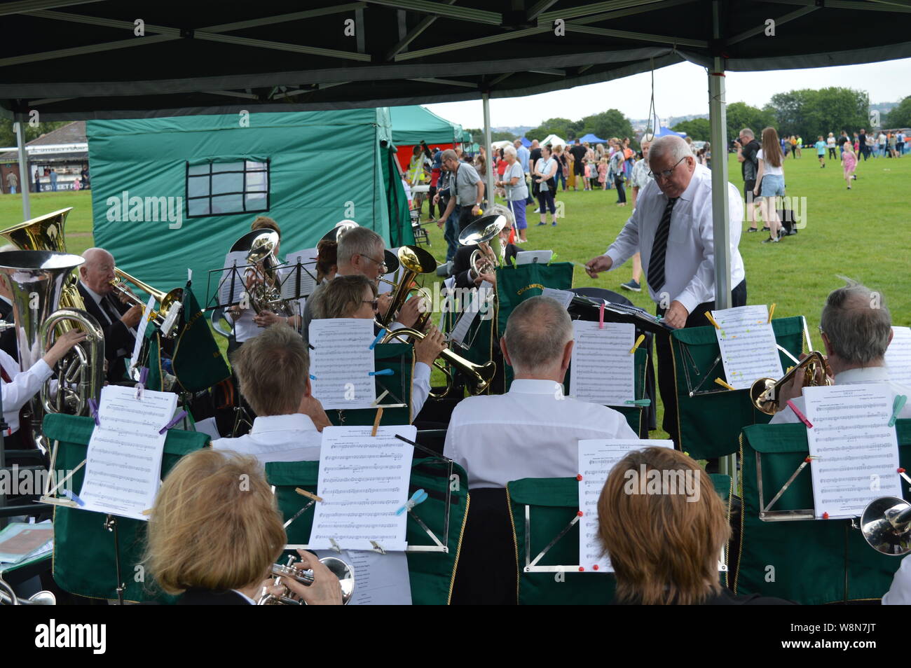 elderly playing instrument in a group lead by a retired old orchestra at Moston Manchester local event British summer time Stock Photo