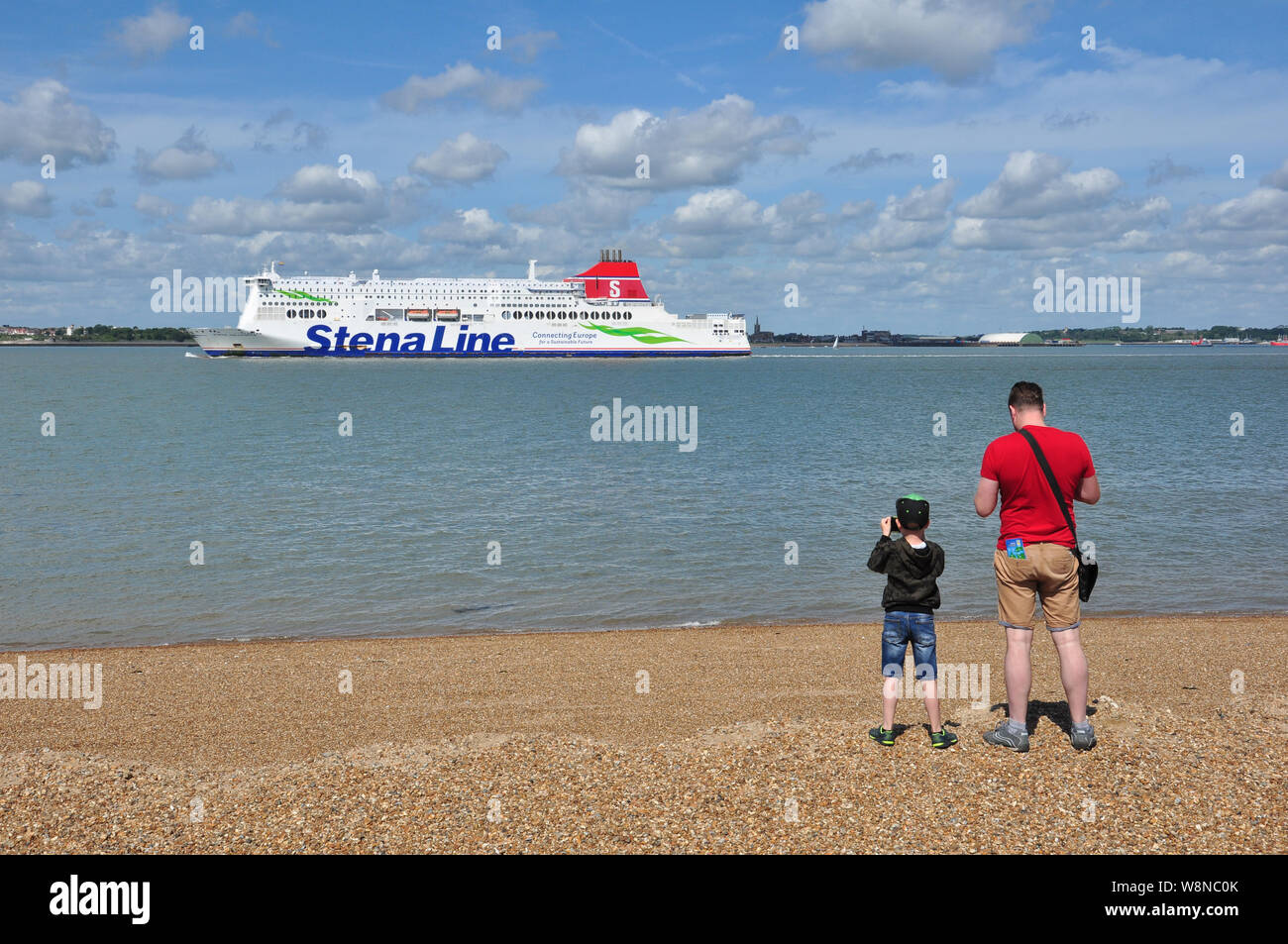 The ferry, Stena Hollandica, departs from Harwich for Hook of Holland  with man and boy watching it go by, (public area), Felixstowe, Suffolk, England Stock Photo